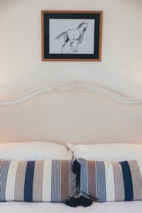 bed with blue striped pillows and a picture of a horse above it
